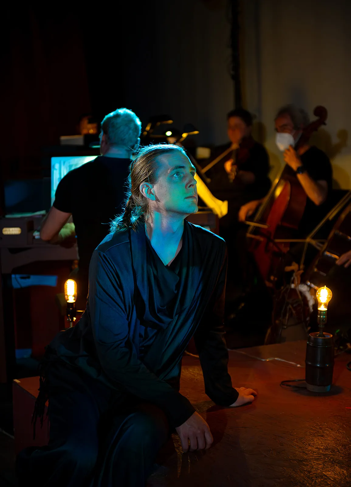 Robin McGinness in Alceste with In Series, lit in blue-green, listening upward
