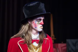 Robin McGinness in clown makeup, black velvet top hat, and red ringmaster's coat