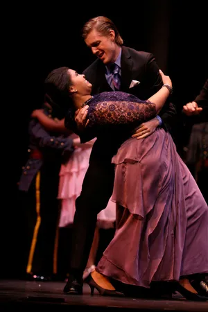 Robin McGinness dipping a dance partner in a lavender gown during a staged ballroom scene